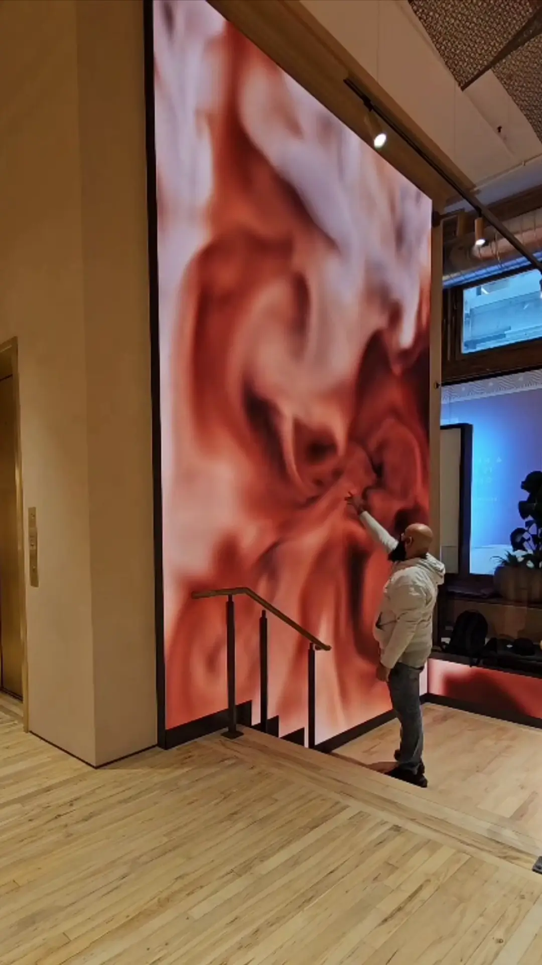 A visitor reaching toward the coffee-and-cream image on the Nespresso New York wall