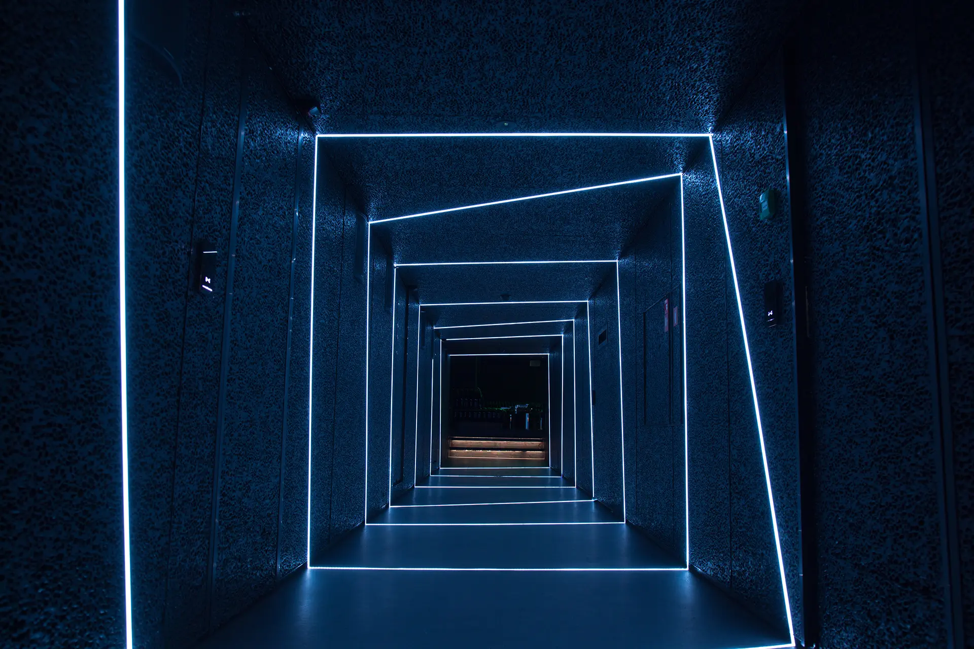 Custom linear light installation forming a tunnel of concentric illuminated frames along a dark corridor