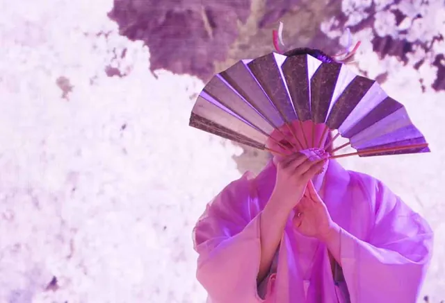 Performer holding a fan within a pink seasonal real-time environment